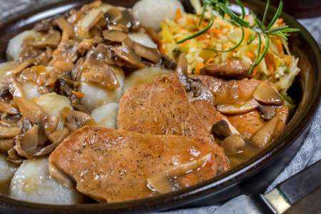 Stewed pork loin with mushrooms, served with Silesian dumplings and salad.の写真素材