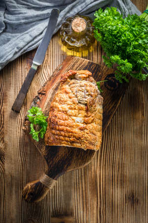 Baked rolled bacon with spices on a wooden chopping board.の写真素材