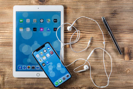 KATOWICE, POLAND - February 23, 2020: Ipad Air 2 and Ipone XS on a wooden background.のeditorial素材
