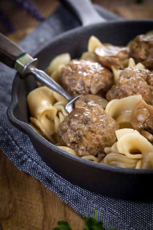 Pork meatballs with noodles in a cast iron skillet. Selective focus.