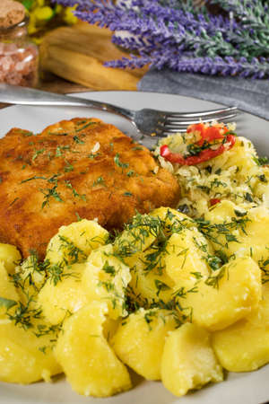 Breaded fish with potato and salad of sauerkraut for dinner. Selective focus.の写真素材