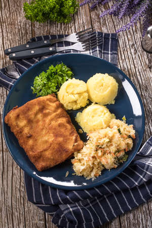 Breaded fish with potato and salad of sauerkraut for dinner. Selective focus.の写真素材