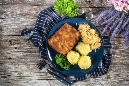 Breaded fish with potato and salad of sauerkraut for dinner. Selective focus.の写真素材