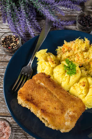 Fried cod fillet served with boiled potatoes and vegetable salad.