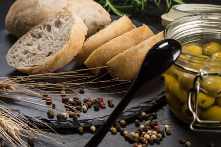 Italian ciabatta bread cut in slices on stone chopping board over dark backdrop.の写真素材