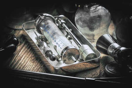 Retro syringe, stethoscope and medical cupping glass on a wooden table. Shallow depth of field....
