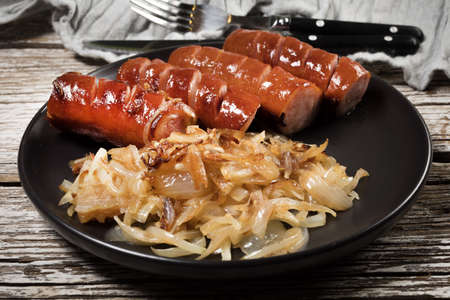 Fried sausage with onion on black plate.の写真素材