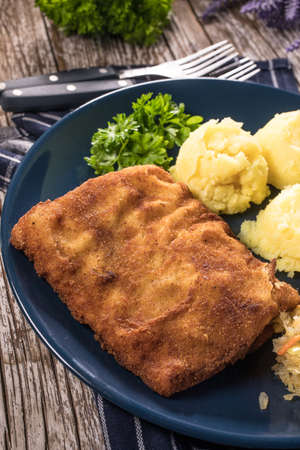 Breaded fish with potato and salad of sauerkraut for dinner. Selective focus.
