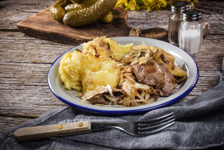 Fried liver with onion and apple, served with boiled potatoes and pickled cucumber.の写真素材