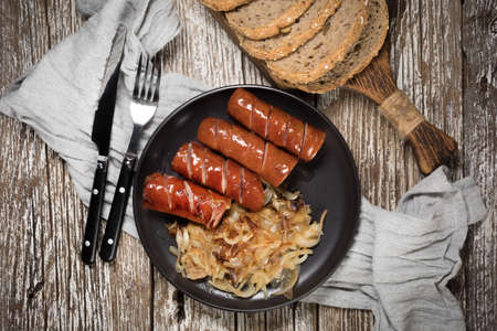 Fried sausage with onion on black plate. Top view.の写真素材