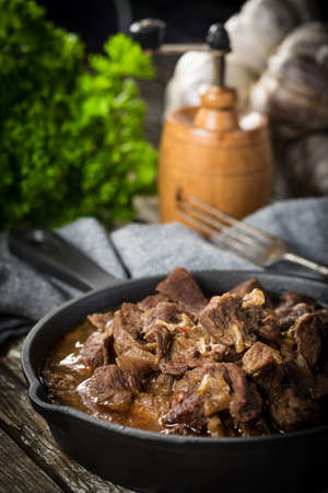 Beef stew in a cast iron skillet - wooden background. Shallow depth of field.の写真素材