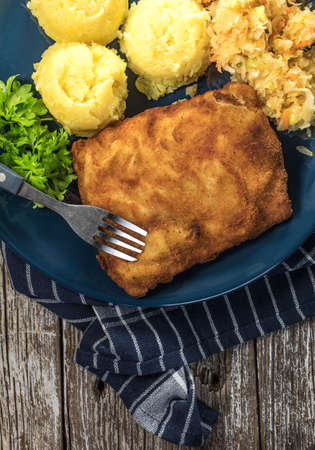 Breaded fish with potato and salad of sauerkraut for dinner. Selective focus.