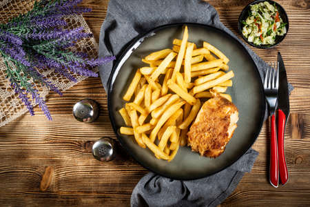 Fried chicken breast stuffed with bacon and cheese served with chips and salad. Small depth of field.の写真素材