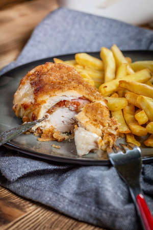 Fried chicken breast stuffed with bacon and cheese served with chips and salad. Small depth of field.の写真素材