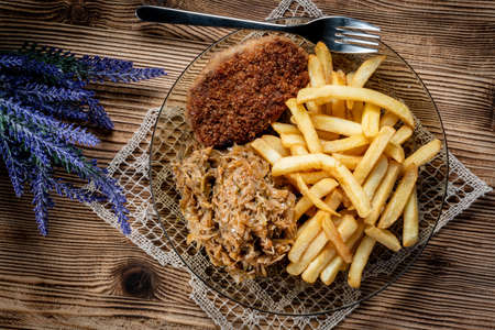 Pork chop in breadcrumbs served with fries and stewed cabbage. Selective focus.の写真素材