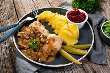Grilled chicken breast with mushroom sauce, served with mashed potatoes and pickled cucumbers.の写真素材