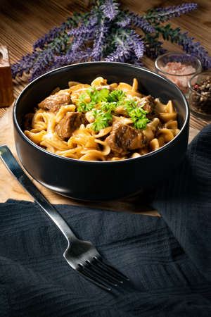 Tagliatelle mosse with beef sauce on wooden table. Dark light.の写真素材