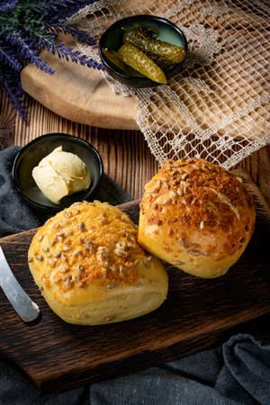 Tasty buns with cheese and sunflower seeds on wooden background.
