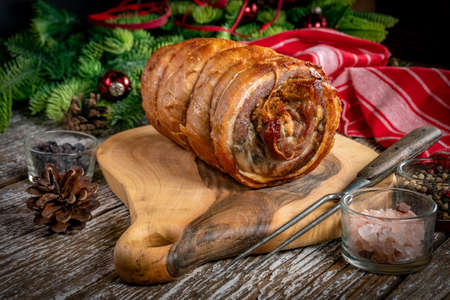 Baked rolled bacon on a wooden chopping board.の写真素材