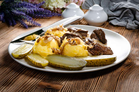 Fried liver with onion, served with mashed potatoes and pickled cucumber.の写真素材
