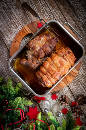 Baked bacon roulade and roasted pork neck in a metal roasting pan.の写真素材