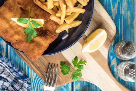 A piece of fried cod with fries on a plate.の写真素材