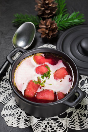 Red borscht soup in a bowl on black background.