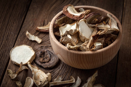 Dried mushrooms in a wooden bowl on a dark background.の写真素材