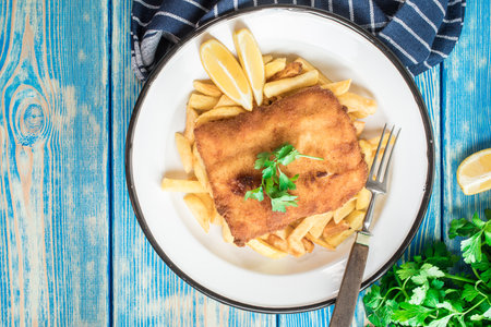 A piece of fried cod with fries on a plate. top view.の写真素材