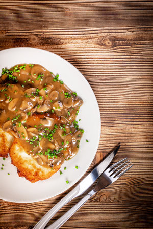 Crispy potato pancakes with mushroom sauce on wooden table.の写真素材