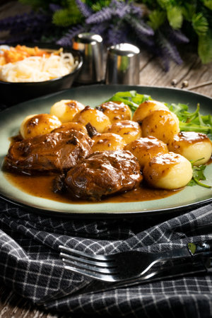 Traditional German braised pork cheeks in brown sauce with mushroom served with Silesian dumplings.の写真素材