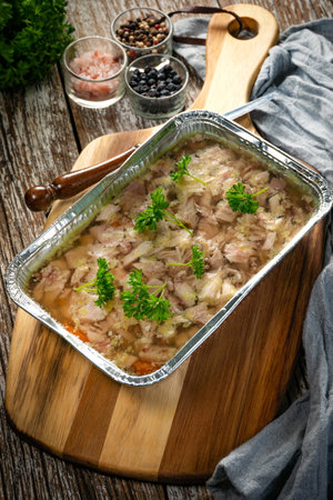 Jelly with shredded chicken meat in a mold on a wooden table.