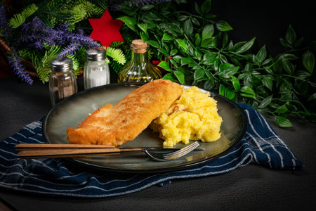 Breaded chicken breast fillet served with boiled potatoes and cucumber slices.
