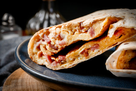 Multigrain tortilla with omelette, sausage and bacon. Shallow depth of field.の写真素材