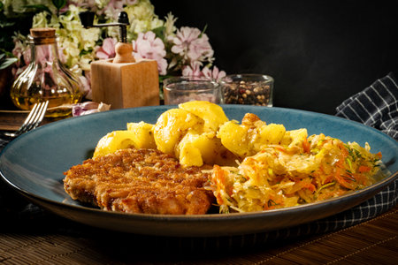 Pork neck cutlet served with potatoes and salad. Shallow depth of field.の写真素材