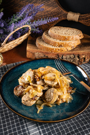 Slices of white sausage stewed with onion on a blue plate. Shallow depth of field.の写真素材