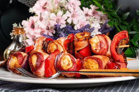 Tasty chicken skewers wrapped in bacon with vegetables.の写真素材
