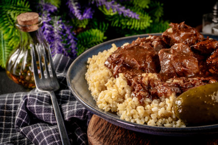 Beef goulash served with bulgur groats poured with dark sauce. Shallow depth of field.の写真素材