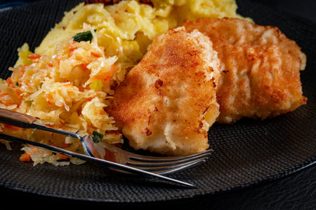 Fried cod fillet served with boiled potatoes and vegetable salad.の写真素材