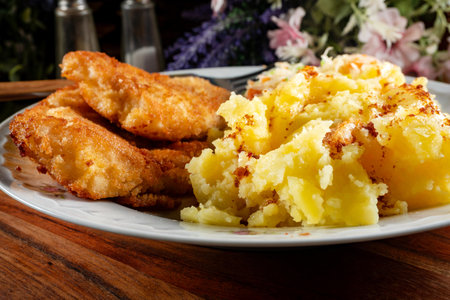 Fried cod fillet in breadcrumbs served with boiled potatoes and vegetable salad..の写真素材