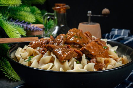 Pasta with beef stew in black bowl. Shallow depth of field.の写真素材