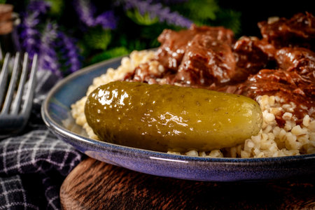 Beef goulash served with bulgur groats poured with dark sauce. Shallow depth of field.の写真素材