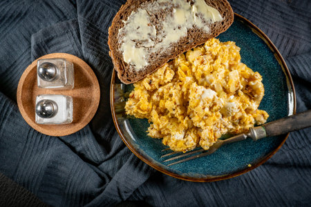 Scrambled eggs with onion served with bread on a blue plate.