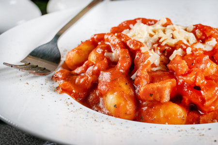 Traditional Italian potato Gnocchi with tomato sauce, parmesan cheese and bacon in the bowl.