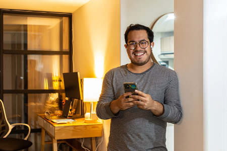 Happy Freelancer Receiving Good News on Phone at Home Officeの写真素材