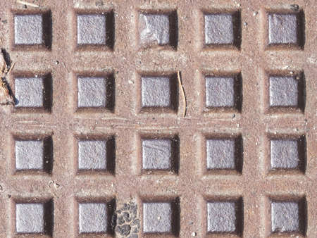 Old dark metal manhole texture with square pattern, background macro, selective focus.