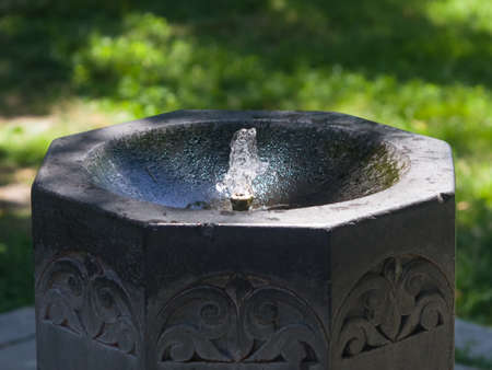 Stone fountain with drinking water close-up, selective focus, shallow DOF.の写真素材