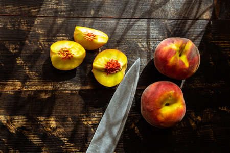 still life with fresh ripe peaches in season on wooden table and kitchen knifeの写真素材