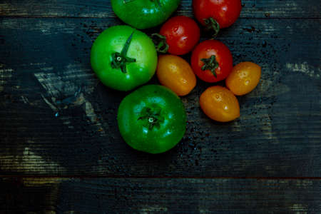 still life with fresh red, green and yellow tomatoes freshly picked from the garden on the wooden...