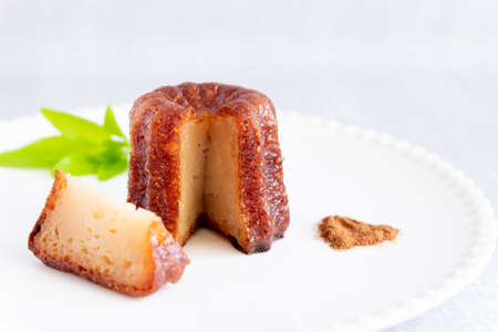 Canele, French confectionery, with a cut loaf, on a white and grey backgroundの写真素材